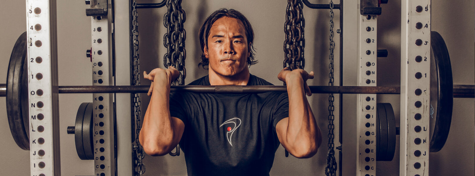 Man lifting weights with intense focus in a gym.