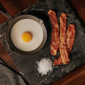 Bacon, and egg, and salt on a cutting board